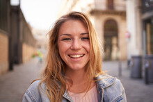 Close up portrait of cheerful attractive young Caucasian woman happy smiling face on street. Female people with joyful expression looking at camera outdoor. Blonde gen z girl posing natural for photo