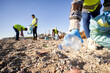 © CarlosBarquero - Group of cleanup volunteers cleaning up waste in nature and holding a garbage bag trash. Close up of activist hand picking up a plastic bottle. Concept of environmental protection.