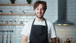 © mahirkart - Portrait of young man with curly hair with with apron looking at camera and smiling at home kitchen