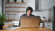 © mahirkart - Focused male sitting in kitchen at home wear wireless headset with microphone having video conference calling on laptop computer talk by webcam, learning study with online tutor