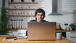 © mahirkart - Happy man sitting in the kitchen having video call conversation through using laptop computer. Share news, talk to family, enjoy webchat virtual meeting