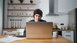 © mahirkart - Focused man working at home in the kitchen working with his laptop, doing research. Busy freelancer working on modern tech notebook device