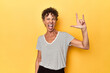 Mid-aged caucasian woman on vibrant yellow showing a horns gesture as a revolution concept.