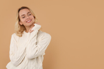 Canvas Print - Happy woman in stylish warm sweater on beige background. Space for text