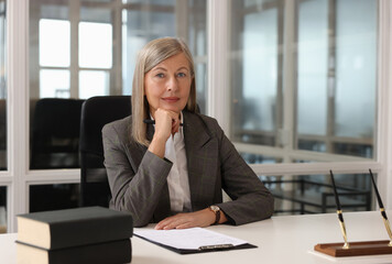 Poster - Smiling woman at table in office. Lawyer, businesswoman, accountant or manager