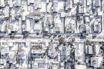 Wall Mural - snow-covered rooftops in suburbs residential area. aerial top view from flying drone.