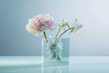 Elegant peony and amaryllis blossoms in a glass cube vase, with submerged greenery creating a dreamy, ice-encased effect