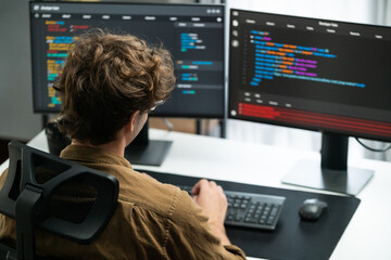 IT developer working online software development on pc monitors at modern home office on coding application screens, creating updated latest program firmware information version concept. Gusher.