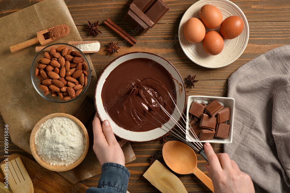 Woman preparing tasty melted chocolate on wooden background