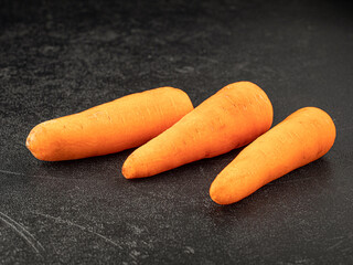 Three fresh carrots on grey background