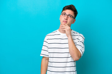 Wall Mural - Young handsome Brazilian man isolated on blue background having doubts