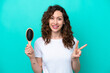 Young caucasian woman holding hairbrush isolated on blue background smiling and showing victory sign