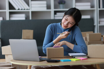 Young Asian woman doing online shopping from home contacting customers for delivery.