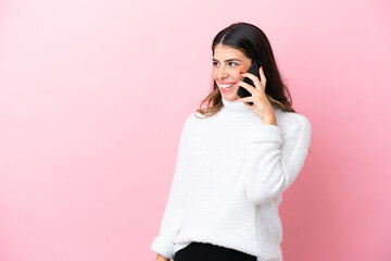 Wall Mural - Young Italian woman isolated on pink background keeping a conversation with the mobile phone with someone