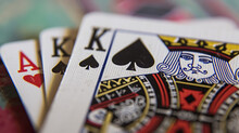 A Close-up Of Playing Cards On A Table, Featuring The King Of Spades.