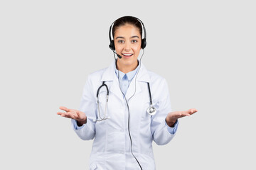 An approachable european doctor wearing a headset and a white lab coat gesturing with open hands