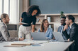 © gstockstudio - Happy group of business people discussing strategy during team meeting at the office desk together