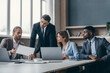 © gstockstudio - Confident business team discussing strategy while having group meeting at the office desk