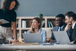 © gstockstudio - Happy group of business people discussing strategy during team meeting at the office desk together