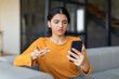 © Prostock-studio - Spam Mailout. Annoyed young indian female looking at smartphone screen