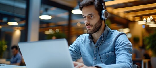 Poster - Attractive male call center worker using laptop in modern office, observing screen with empty space for a hotline support service.