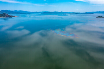 Top view of the turquoise water of a mountain lake. Clean clear water with streaks on the bottom. Patterns from a mountain river. The color shimmers from blue-green to blue. Trees in the water. Issyk