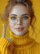 Optymizm w Żółtym. Zdjęcie dziewczyny w okularach o żółtej oprawie i golfie, z uniesionym palcem wskazującym, symbolizuje optymizm i pozytywne podejście do życia.
