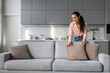 © Prostock-studio - Woman arranging pillows on couch in a clean, modern home