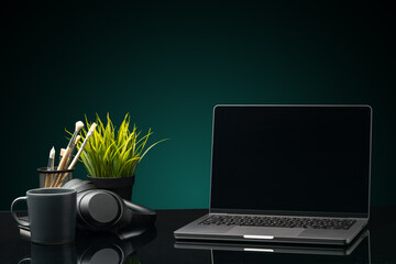 Canvas Print - Laptop with black screen on working desk with cup and earphones on black background