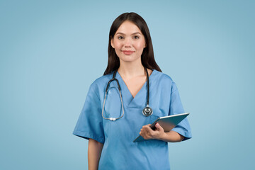 Wall Mural - Happy nurse in blue with stethoscope and tablet, blue background