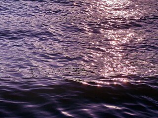 Dark purple glittering ripples water at night. 