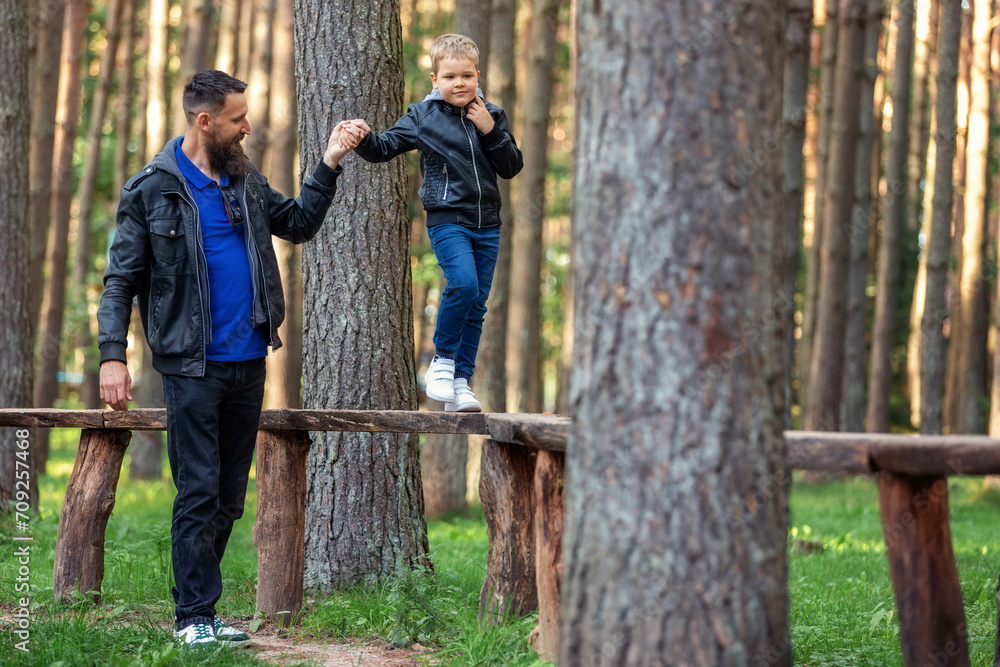 A father leads his son through an obstacle course on a walking path. A ...