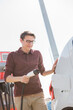 © scharfsinn86 - A man stands at the charging station and holds a plug of the charger for an electric car.