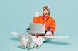 Full body winner young IT woman in windbreaker jacket hat ski goggles mask sit with snowboarding use laptop pc computer travel rest spend winter season in mountains isolated on plain blue background