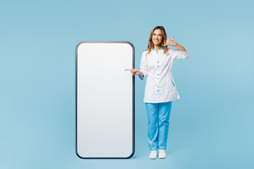 Full body doctor woman wear white medical gown suit work in hospital clinic office big huge blank screen mobile cell phone say call back isolated on plain blue background Health care medicine concept