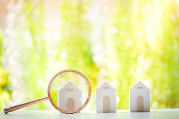 Wall Mural - Magnifying glass with home model put on the wood on bokeh background, Loan for real estate and searching for buy a new house to family in the future concept.