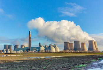 Drax, North Yorkshire, UK in Winter. Plumes of water vapour emitting from the cooling towers of a Power plant, Biomass Plant, Drax, Selby, North Yorkshire. Clean blue sky background. Space for copy.