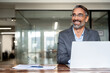 © Stock 4 You - Portrait of mature Indian or Latin business man ceo trader using laptop computer, typing, working in modern office. Middle-age Hispanic smiling handsome businessman entrepreneur looking aside,dreaming