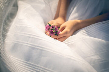hands of a girl holding some flowers on her first communion dress