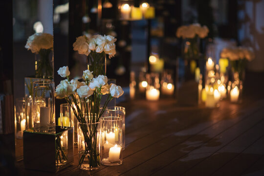 View of elegant expansive white flowers and candles decoration for wedding party. the wedding ceremony in the open air. Luxury and beautiful wedding decor. Decor details with lights at evening.