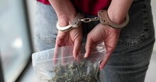 Woman In Handcuffs Holds Pack Of Dry Marijuana Behind Back