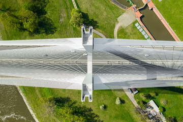 Wall Mural - Famous cable-stayed Redzinski Bridge over blue flowing river among lush green forests. Scenic nature and urban infrastructure near Wroclaw aerial view