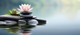 Beautiful lotus or lily flower and stack of stones on water surface blur background. Generate AI