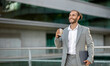 © Prostock-studio - Relaxed young businessman holding laptop and cup of coffee while walking outdoors