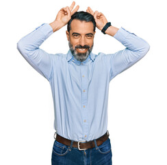 Sticker - Middle aged man with beard wearing business shirt posing funny and crazy with fingers on head as bunny ears, smiling cheerful