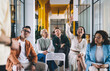 © BullRun - Group of diverse colleagues communicating with speaker at workplace