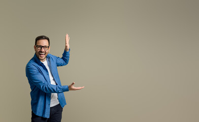 Wall Mural - Portrait of cheerful businessman laughing and advertising new product on isolated gray background