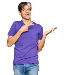 Sticker - Young hispanic man wearing casual clothes amazed and smiling to the camera while presenting with hand and pointing with finger.