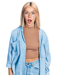 Wall Mural - Beautiful young blonde woman wearing glasses afraid and shocked with surprise and amazed expression, fear and excited face.