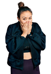 Wall Mural - Young hispanic girl wearing sportswear laughing and embarrassed giggle covering mouth with hands, gossip and scandal concept